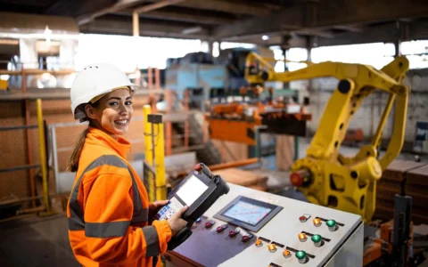Ingeniera en automatización y control industrial operando maquinaria robotizada desde panel de control en planta de producción.