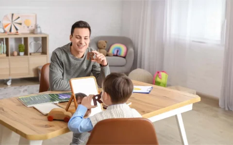 Psicopedagogo trabajando con niño en sesión de aprendizaje usando letras y espejo.