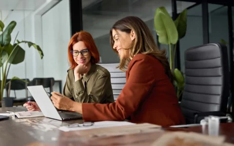Dos profesionales en finanzas trabajando juntas frente a un computador.