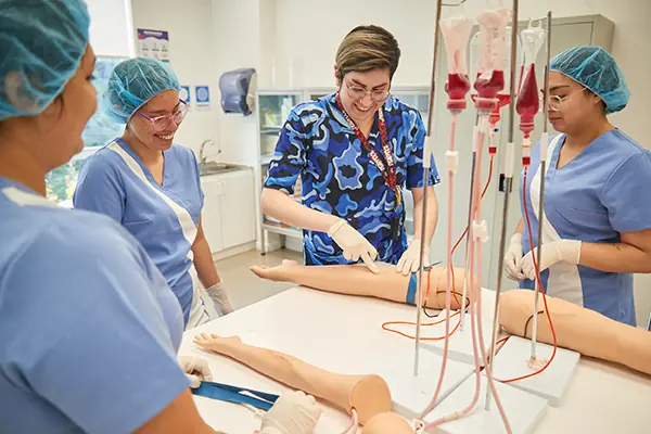 “Estudiantes de enfermería practican procedimientos clínicos en un laboratorio con maniquíes y equipo médico.